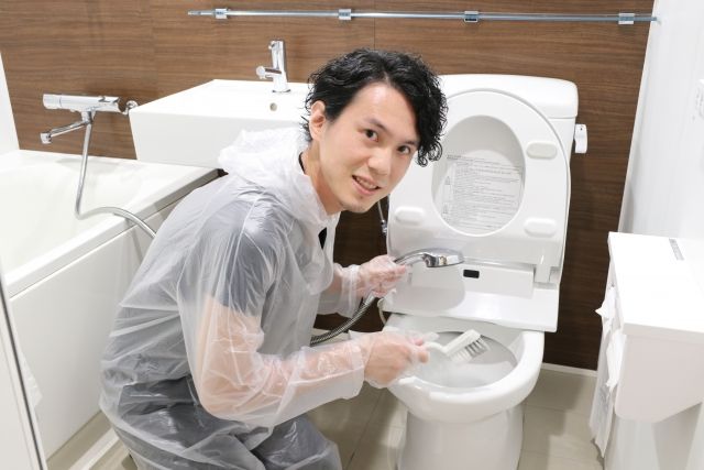 ウォシュレット付きトイレを掃除する男性