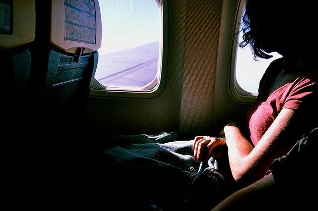 飛行機の機内窓から外を見る女性